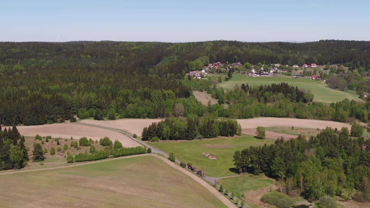 Wide drone shot of green hills and small village in countryside near Prague, on a sunny day
