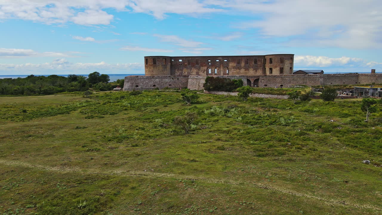 volando sobre los exuberantes campos hacia la fortaleza del castillo de borgholm durante el día en öland, suecia