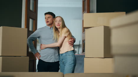 owners looking new house full of carton boxes. couple enjoy buying modern flat.