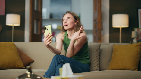 Chica-Coqueteando-Videollamada-En-El-Sofá-Del-Teléfono-Móvil.-Mujer-Sonriente-Gesticulando-Las-Manos-Hablando