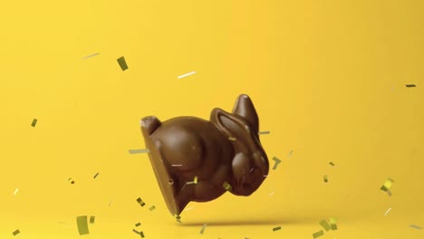 animación del conejo de pascua de chocolate cayendo y confeti dorado volando sobre un fondo amarillo