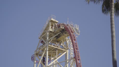 beautiful shot of a roller coaster gliding over the steep lift hill, and then plunging back down towards earth