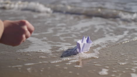 main de femme plaçant un bateau origami dans la mer