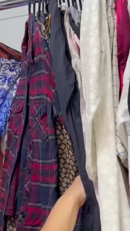 a woman chooses clothes in a secondhand store buying used clothes a woman chooses clothes in a secondhand store buying used clothes shooting medium plan