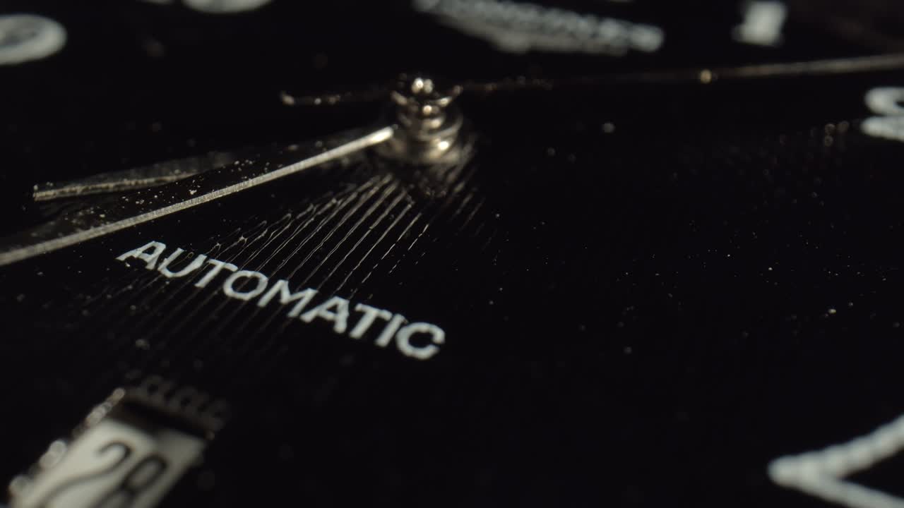 A macro shot of metal seconds hand on the black dial indicates the time. The concept of instruments for measuring time. Watch with logo.