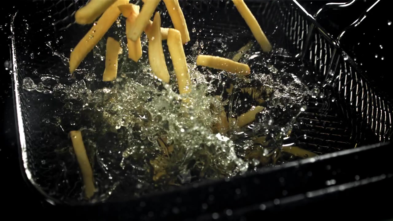 Golden French Fries Dropping into Bubbling Hot Oil in Slow Motion