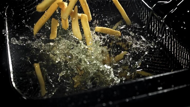 Golden French Fries Dropping into Bubbling Hot Oil in Slow Motion