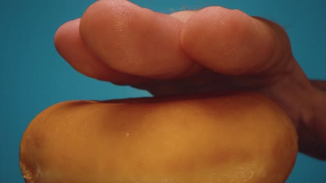 man's hand pressing a freshly baked donut