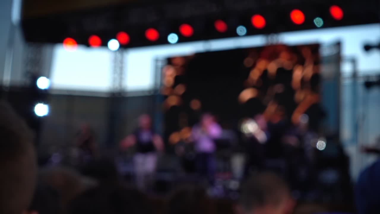 Concerto sul palco. Folla di persone e musicisti sulla scena. Fuori fuoco