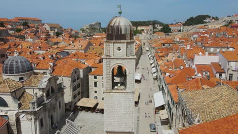 dubrovnik, croacia: iglesia franciscana junto a la calle stradun y el monasterio en dubrovnik, croacia - casco antiguo en verano, al mediodía con turistas paseando por la carretera