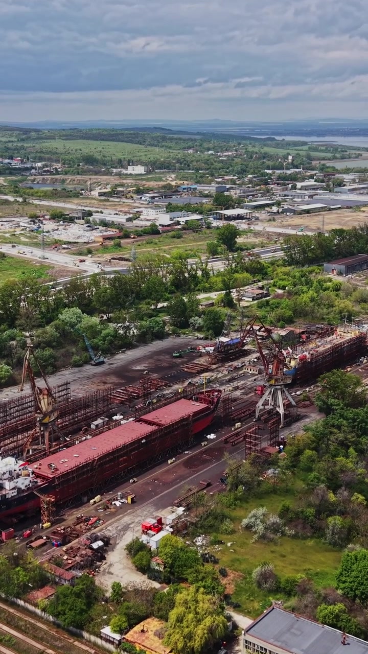 Vista di un'area industriale e di una costa con uno specchio d'acqua sullo sfondo.