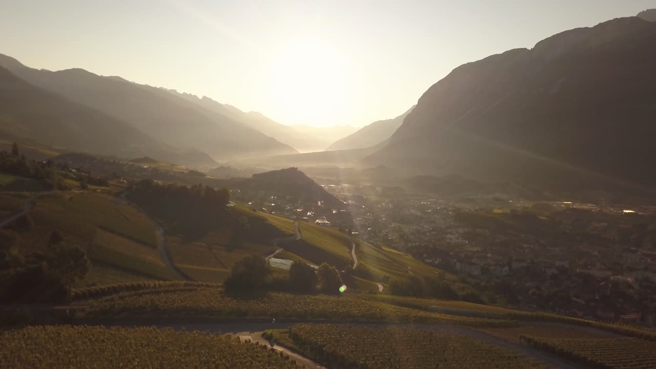 Ripresa con drone al mattino presto con il sole che sorge in lontananza su una splendida valle montana a Lavaux Oron, Svizzera, in 4k