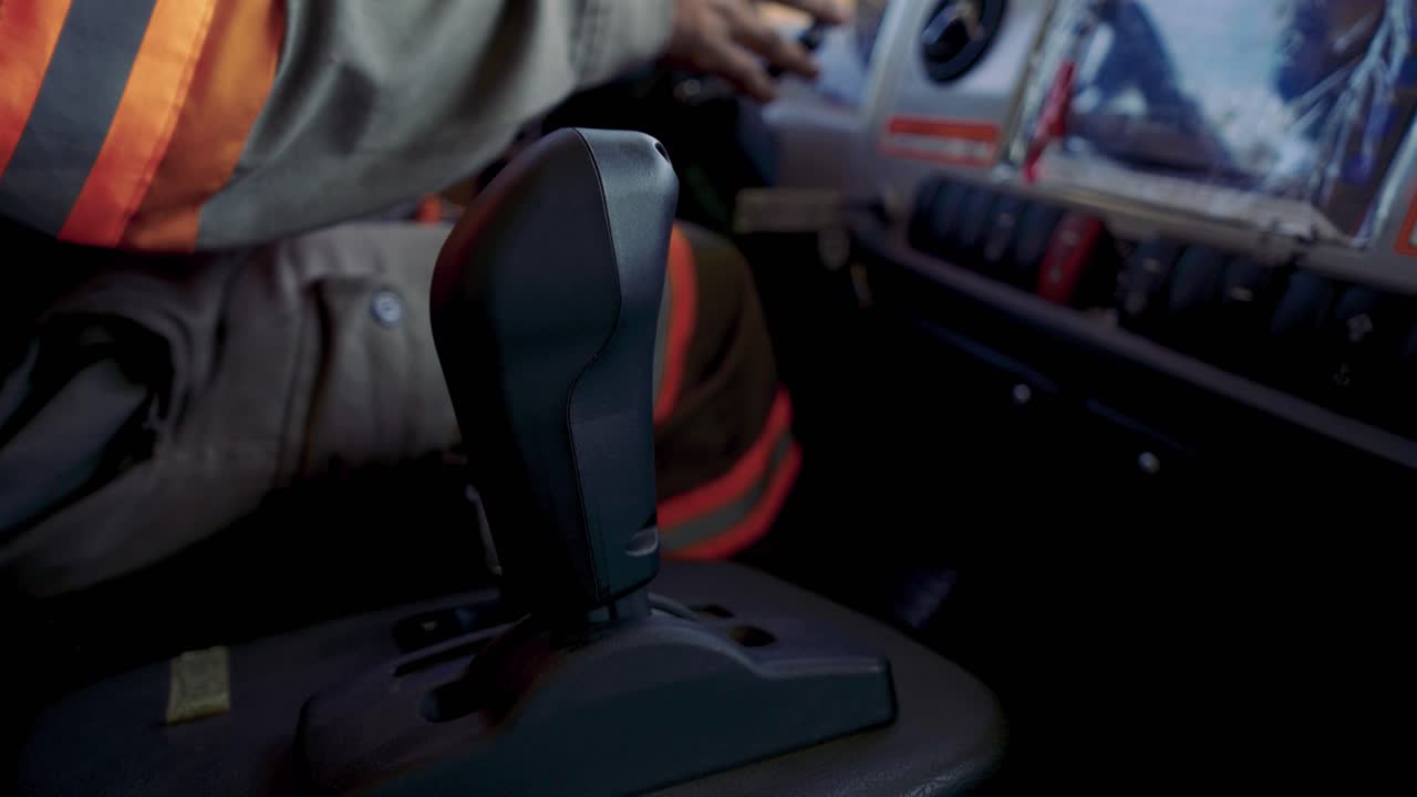 Still closeup of gear stick and driver's arm on the steering wheel inside an NHL TR50E EV mining dump truck in Pakistan