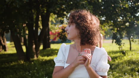 mujer trayendo flores y besando a su pareja al aire libre