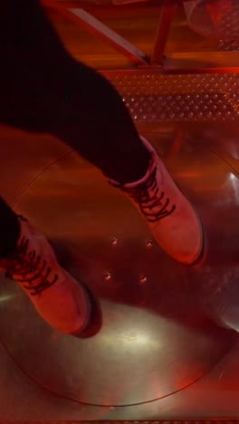 feet on a reflective metallic spinning platform