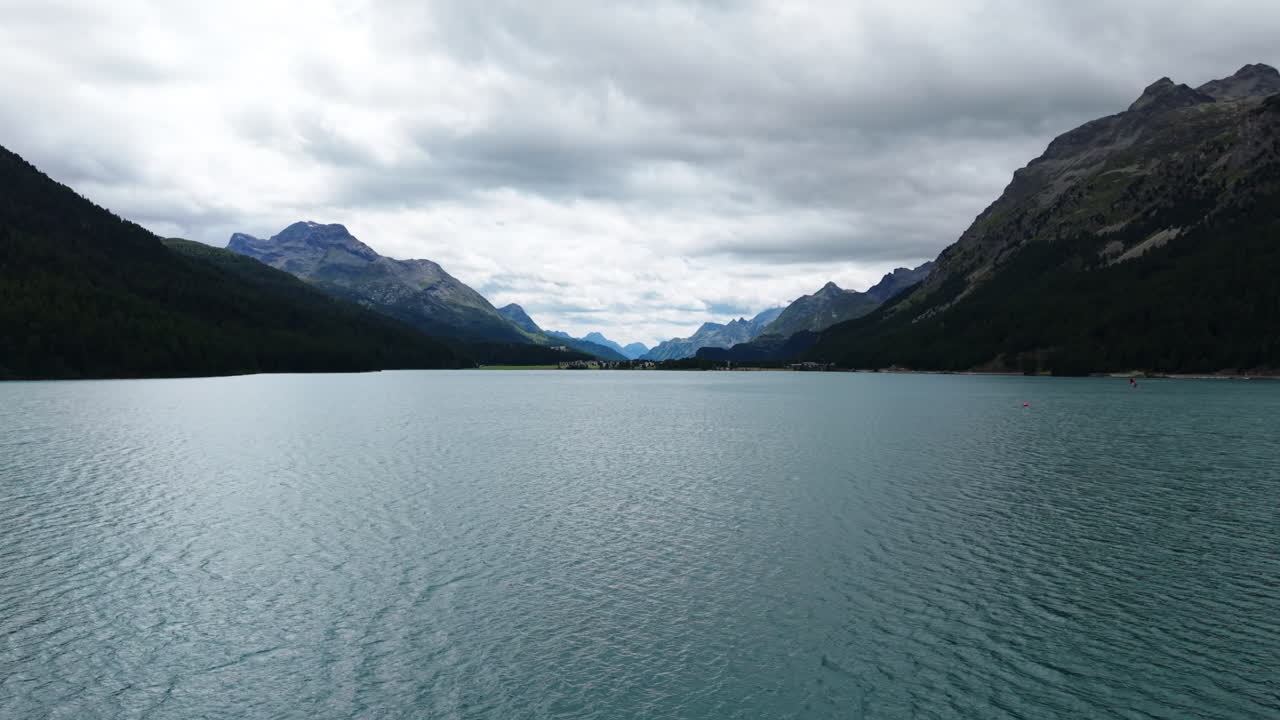 Serene Swiss lake with mountains under cloudy skies, calm and tranquil