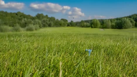 un club de golf frappe une balle de golf au ralenti. des gouttes de rosée matinale et des particules d'herbe s'élèvent dans l'air après l'impact.