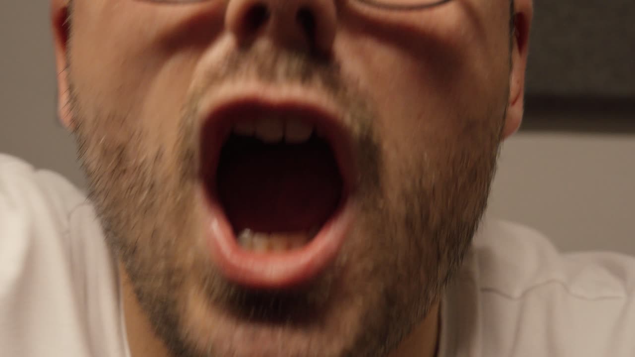 An aggressive man screams and waves his hands in anger during an intense close-up shot, showing strong emotion and frustration