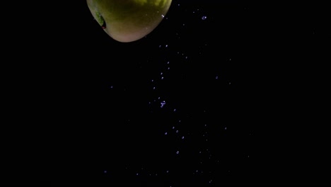 apple diet concept, cinematic shot of green apple falling into the water, background of a single fruit inside water