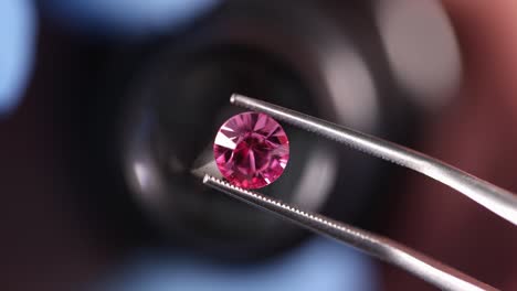 gloved jeweler holds pink gemstone tweezers and examines through magnifying glass 4k movie