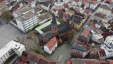 people and colorful houses around protestant gothic stiftskirche church at old city of kaiserslautern, germany