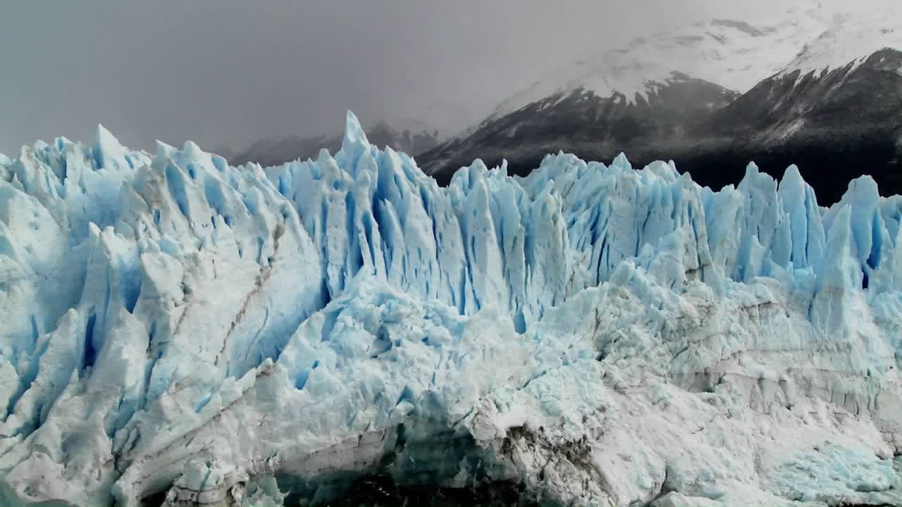 험준한 산들을 배경으로 서 있는 빙하의 뾰족한 꼭대기