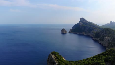 Vista-Panorámica-Aérea-De-Los-Acantilados-Boscosos-De-Cap-De-Formentor-Con-Un-Vasto-Océano-Azul-Tranquilo-En-El-Fondo