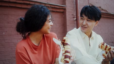 couple eating hot dogs outdoors