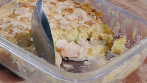 close slow motion shot of spooning fish pie from a cooking dish