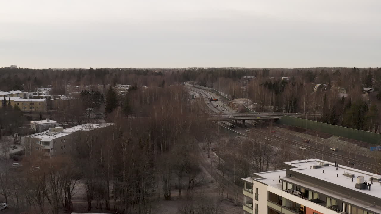 Aerial, drone shot over building overlooking cars on highway Vihdintie 120, cloudy day, in Pitajanmaki, Helsinki, Uusimaa, Finland