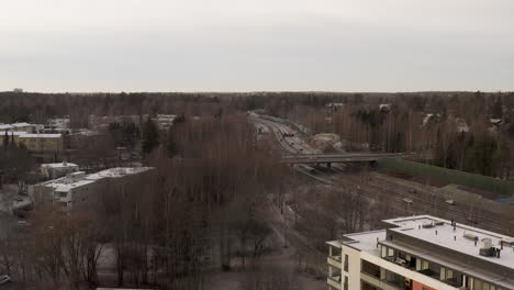 aerial, drone shot over building overlooking cars on highway vihdintie 120, cloudy day, in pitajanmaki, helsinki, uusimaa, finland