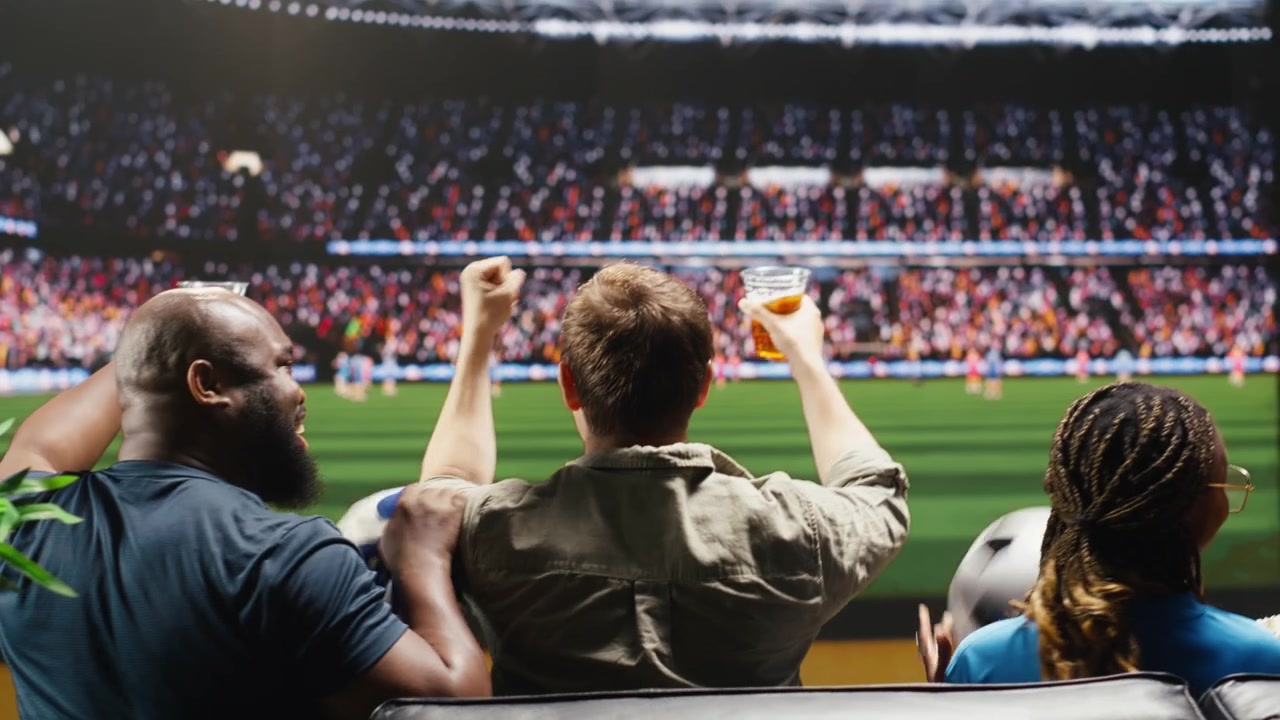 Primer plano de aficionados al fútbol viendo un partido en casa en una retransmisión deportiva inmersiva