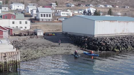 group of tourist returning kayaks at rental place in small icelandic town, aerial