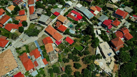 Orange-roof-houses-in-Greek-village,-agriculture-farm-land,-aerial-top-down-view