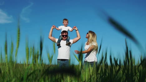 la familia feliz corre y sonríe en el campo con su hijo riendo y tomándose de las manos. hijo sentado en el látigo