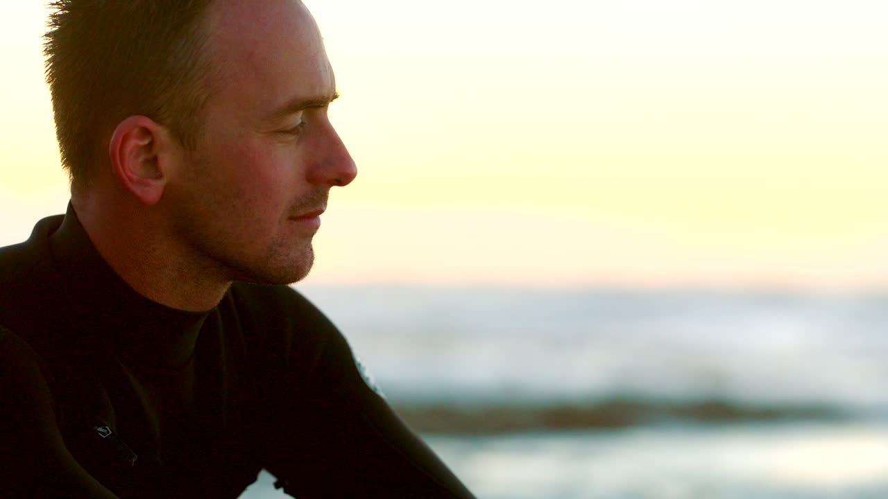 atractivo surfista masculino en un traje de neopreno en la playa