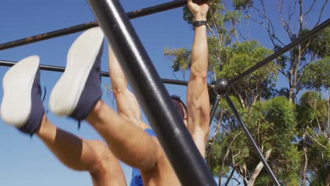 hombre caucásico en forma haciendo ejercicio afuera, haciendo levantamientos de piernas en un marco de escalada