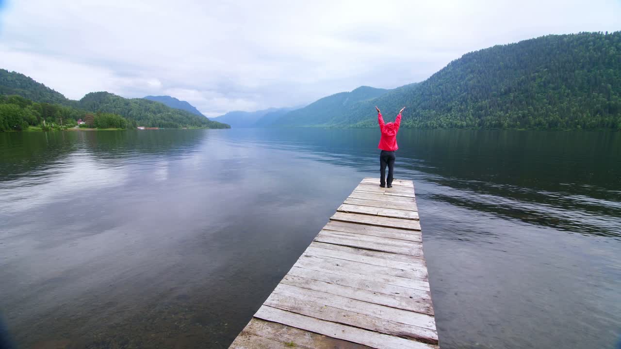 Person on a wooden dock overlooking a serene mountain lake