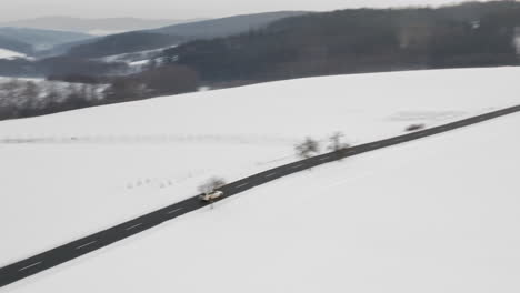 Tracking-Luftaufnahme-Des-Autofahrens-Auf-Der-Straße-In-Unberührter-Winterlandschaft,-Schneebedeckte-Landschaft-In-Europa