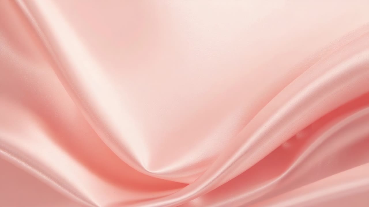 Tessuto di raso rosa increspato che reagisce al cambiamento della luce soffusa dello studio, adagiandosi in delicate pieghe