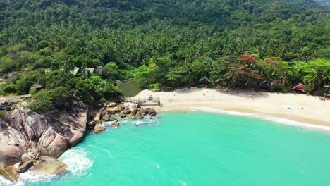 beautiful pristine exotic beach alongside big cliffs naturally caved by turquoise lagoon on tropical island with palm trees forest in thailand