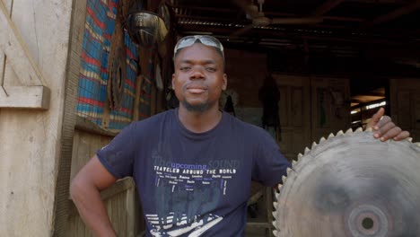 african saw metal worker smiles at close up camera in wooden workshop in ghana