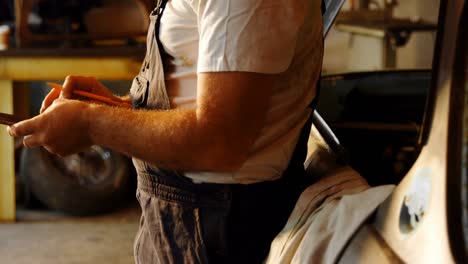 male mechanic using mobile phone in garage 4k