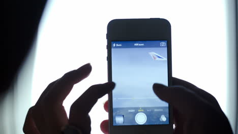 mujer tomando fotos con teléfono inteligente desde un avión volador
