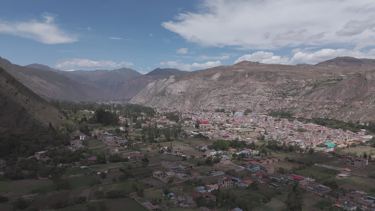 Drone shot above Urubamba Peru near Cuzco between the mountain on a bright day with clouds LOG