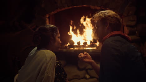 couple resting together fireplace in comfort wooden house. lovers talk at home.