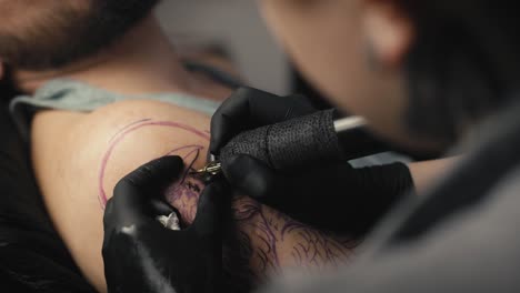 close up of female artist tattooing arms of her customer.