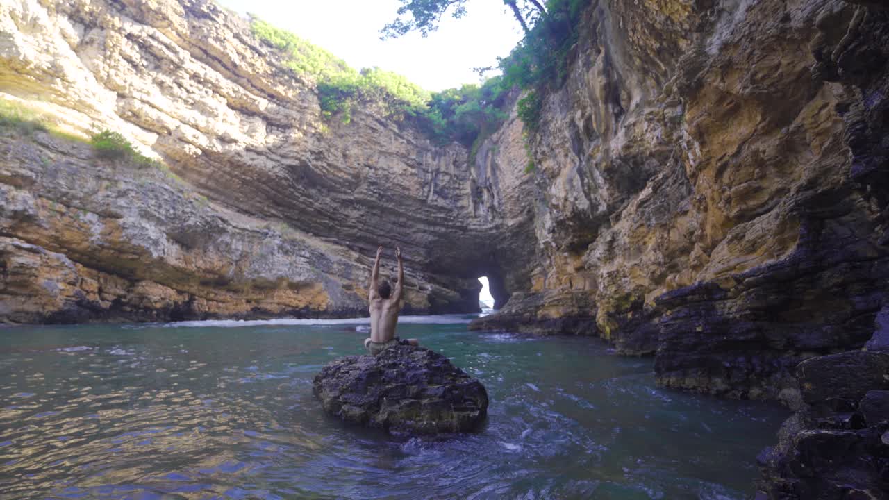 joven de vacaciones en la cueva costera de la playa.