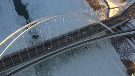 Caída-Aérea-Volar-Sobre-Vista-De-Pájaro-Dolly-Rodar-El-Soleado-Iluminado-Blanco-Walter-Dale-Moderno-Corbata-Arco-Puente-Con-Tráfico-Ligero-Agrietado-Helado-Norte-Saskatchewan-Río-Cubierto-De-Nieve-Diseño-De-Pasarela-Futurista