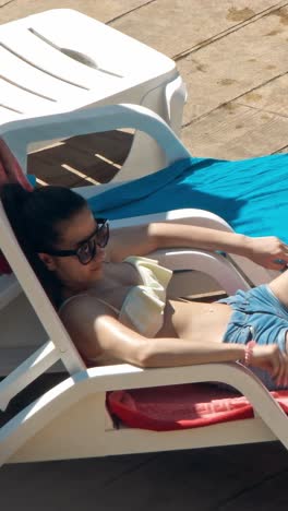 beautiful young women relaxing on the deck chair near the pool